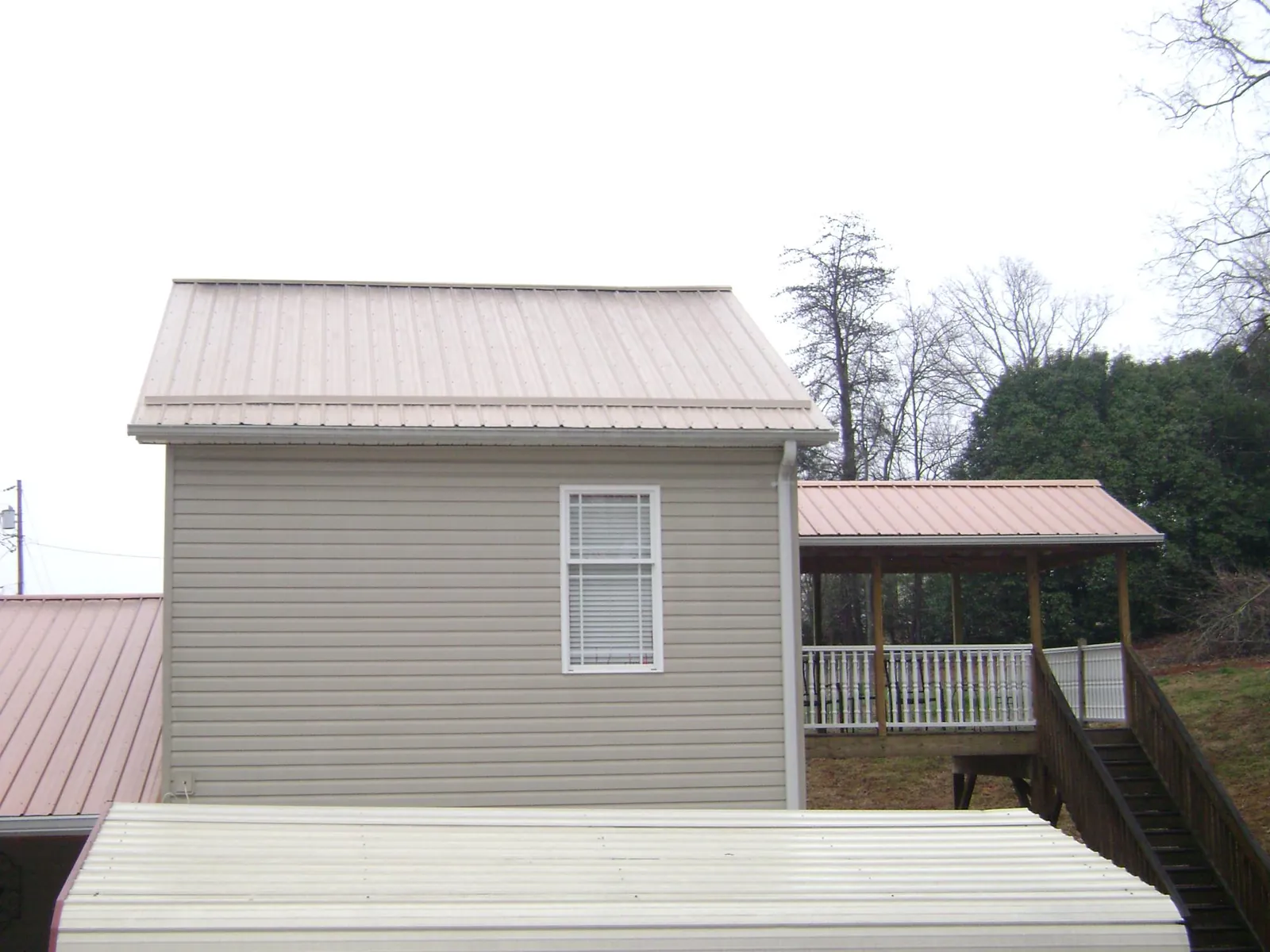 Tan metal roofs on a two story addition and attached porch, from a Roof Replacement job in Braddock Heights