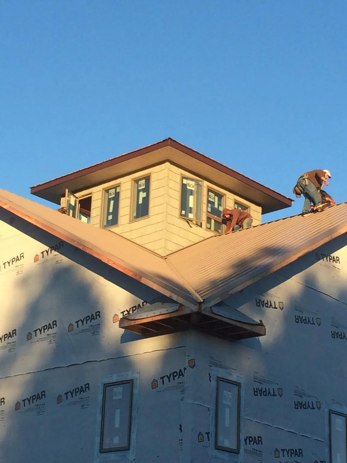 Roofers working around a rooftop cupola on a new metal roof at sunset — Roof Waterproofing in Braddock Heights by Roofing Brothers